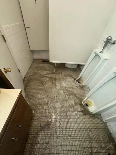 Commercial restroom tile floor with dirty stained grout before deep cleaning