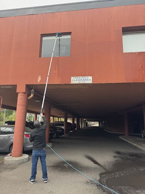 TBM technician using water-fed pole system for high-reach window cleaning
